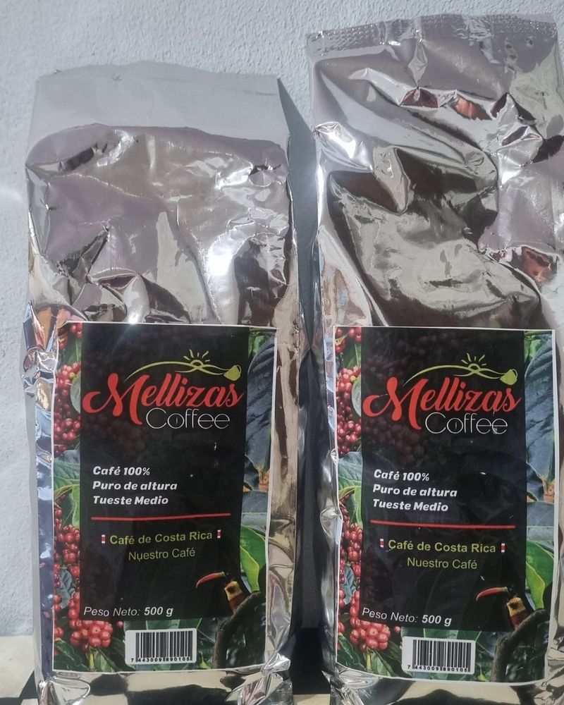 Dos bolsas plateadas de 500 g de Mellizas Coffee de frente, con la etiqueta a color, sobre un piso de cuadros blanco y negro