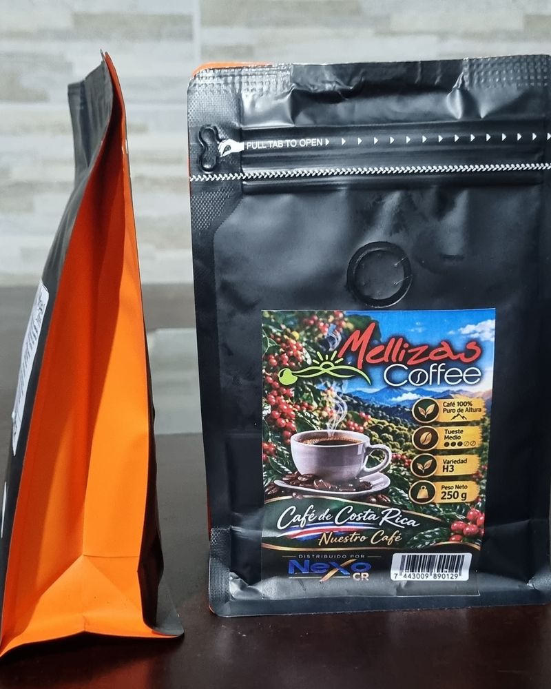 Bolsa de 250 g de Mellizas Coffee de frente sobre una mesa, con otra bolsa de lado que muestra el fuelle naranja